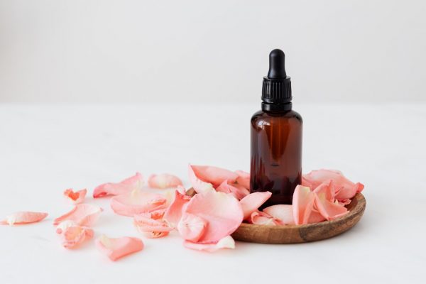 A bottle of Pure Geranium Essential Oil For Skin 15ml in a wooden bowl.
