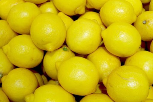 A close-up view of numerous bright yellow lemons tightly packed together, highlighting their fresh, smooth texture and the Lemon Pure Aroma Essential Oil they contain.