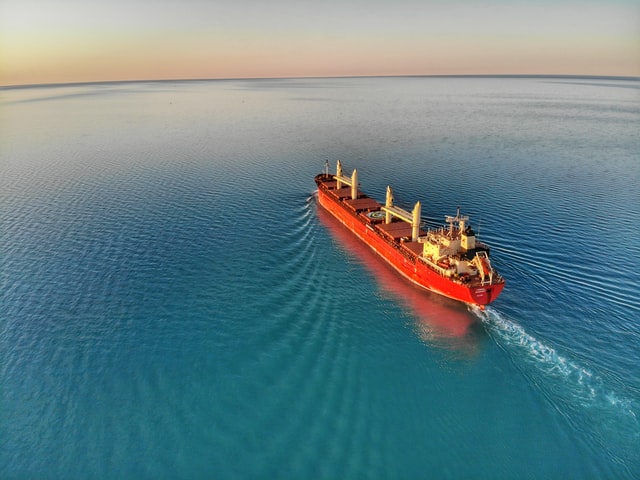 An aerial view of a red cargo ship in the ocean, essentials of Australia.