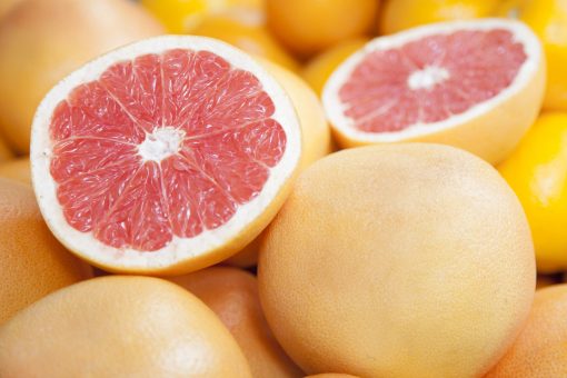 A close-up of ripe grapefruits, with one halved to reveal the juicy pink interior, evocative of the natural essence captured in Grapefruit Essential Oil l 100% Pure l 15ml.