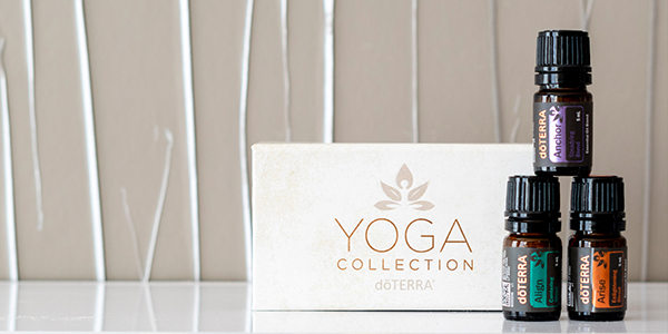 Three essential oil bottles labeled doterra next to a box marked 'Yoga Collection' on a white surface, with a blurred beige background.