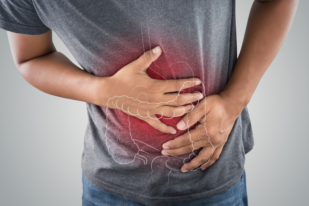 Person holding their stomach in pain with a transparent overlay showing internal organs, including intestines and stomach, indicating digestive discomfort possibly relieved by doterra essential oils.
