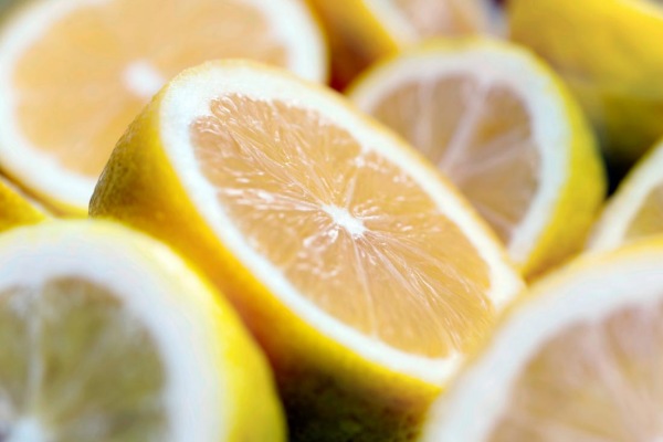Close-up of freshly cut lemon halves and slices, showcasing the bright yellow rind and translucent, juicy interior, reminiscent of the fresh scent captured in doTERRA essential oils. The focus is on