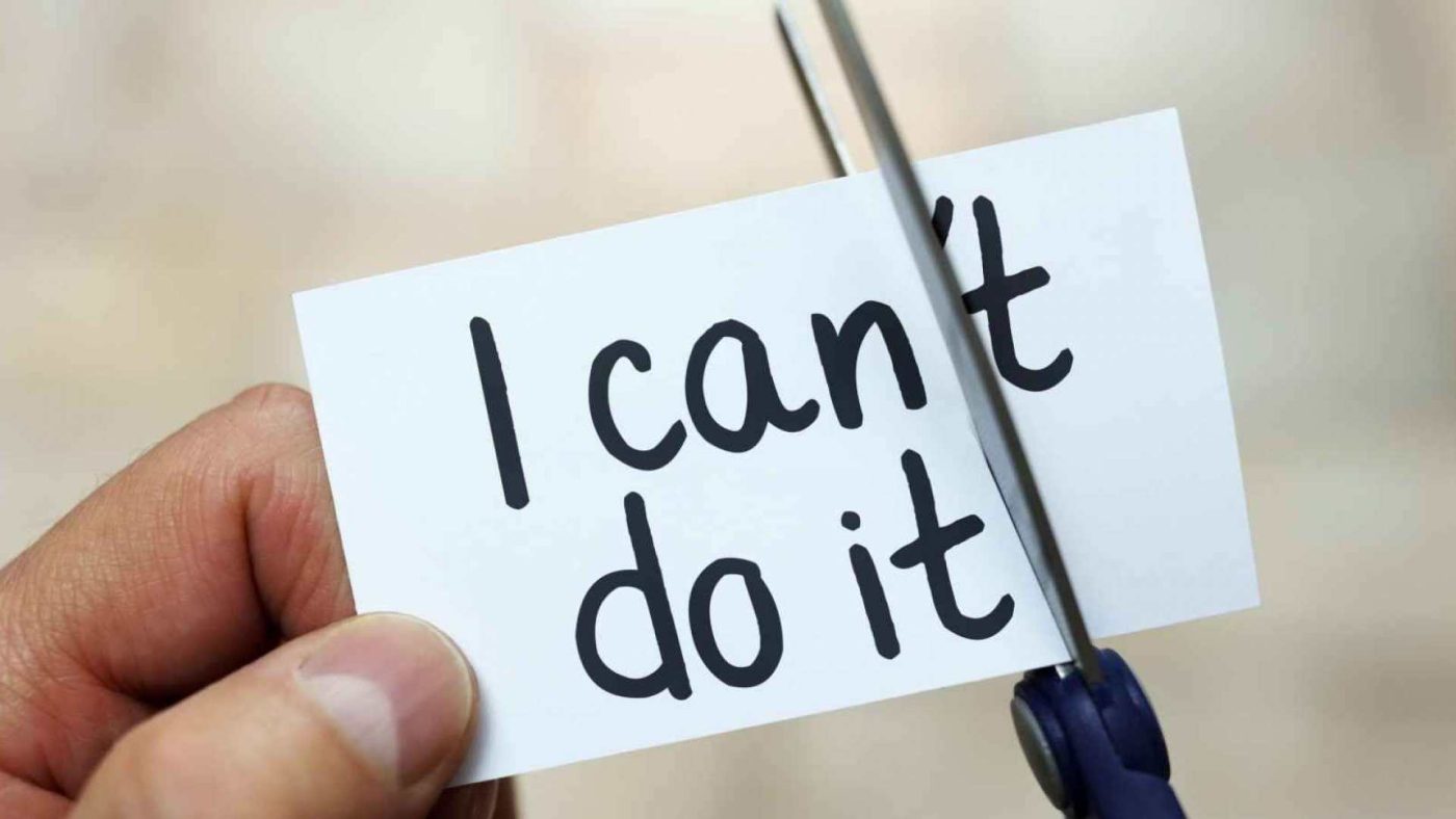A person holds a card with "i can't do it" written on it, and scissors are cutting the word "can't," symbolizing a change to a positive mindset inspired by Earthsun Essentials