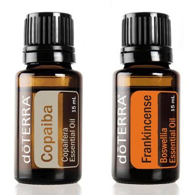 Two bottles of doTERRA essential oils isolated on a white background. The left bottle is labeled "Copaiba oil," and the right bottle is labeled "Frankincense." Each bottle contains